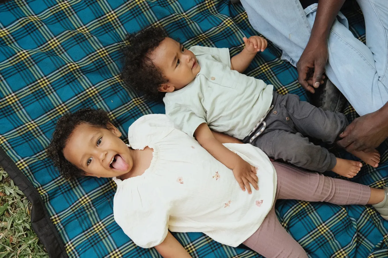 Two children relaxing together on a blue picnic blanket